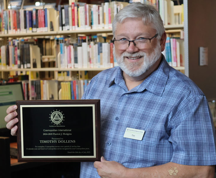 Tim Dollens holds up a plaque from Cosmopolitan International