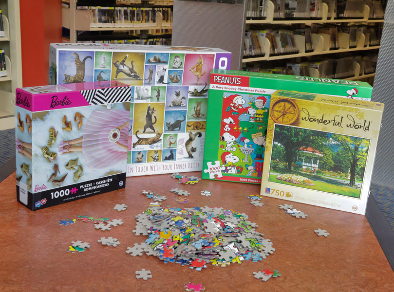 jigsaw puzzles for different age groups arranged on a table with a pile of pieces in front